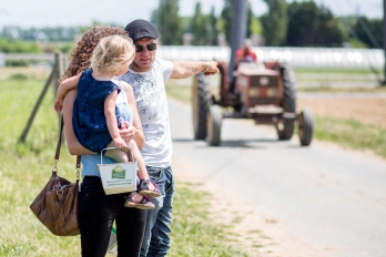 Couple avec petite fille à la cueillette de Puiseux-Pontoise, l'homme montrant un tracteur à la fillette