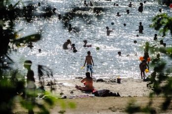 Plage de lÎle de loisirs, baigneurs et reflets sur l'eau entre les arbres