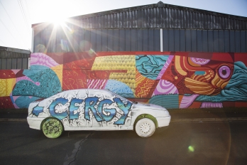 Voiture taguée "Cergy" devant palissade street art