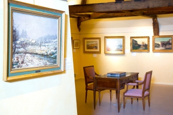 Salle du musée William Thornley avec un bureau et deux fauteuils anciens et des tableaux au mur
