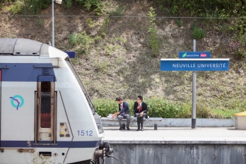 Deux étudiants assis sur un banc sur le quai de la gare Neuville Université